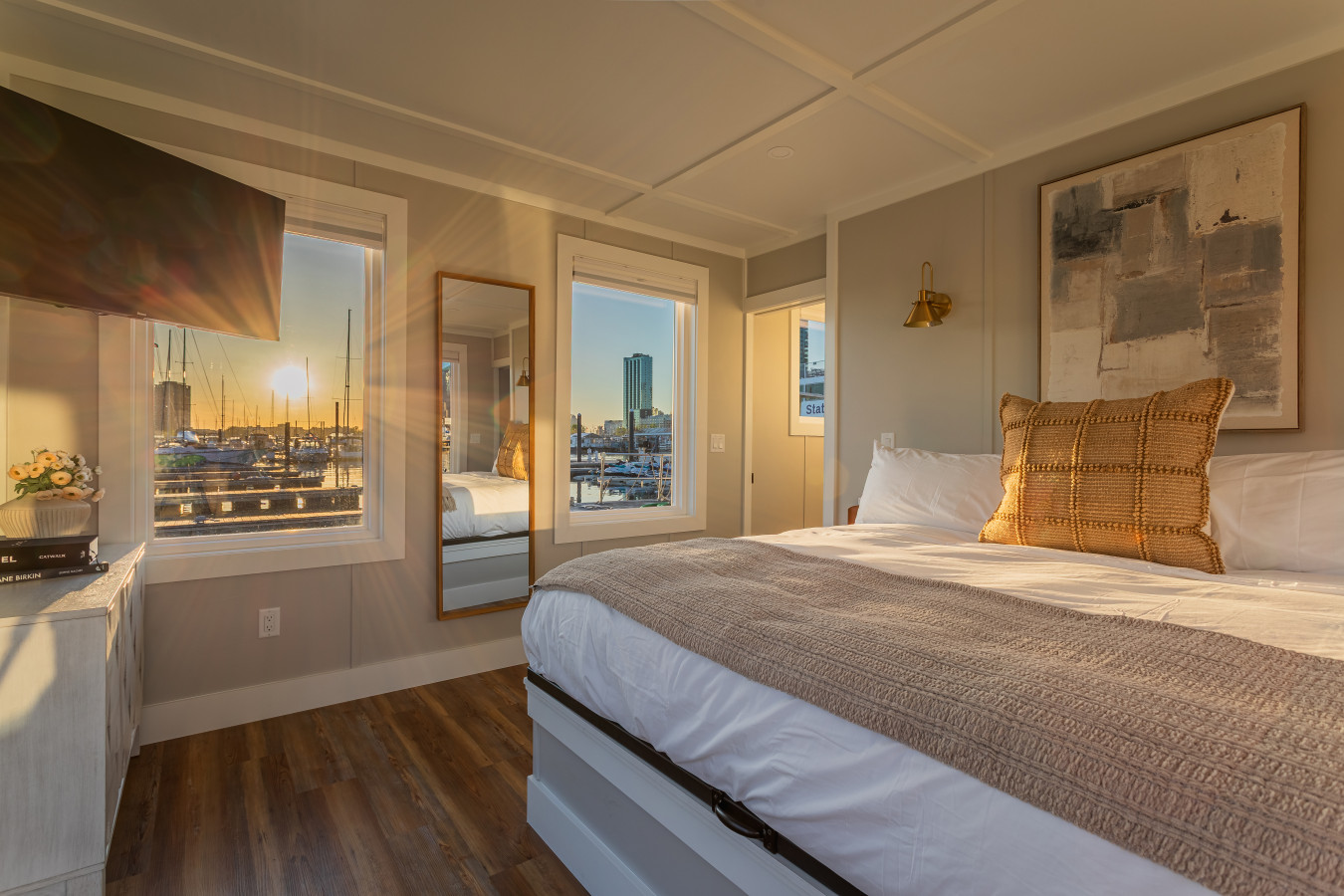 Golden hour settles into the king bedroom as the sun drops over the marina, filling the room with warm light from every window.