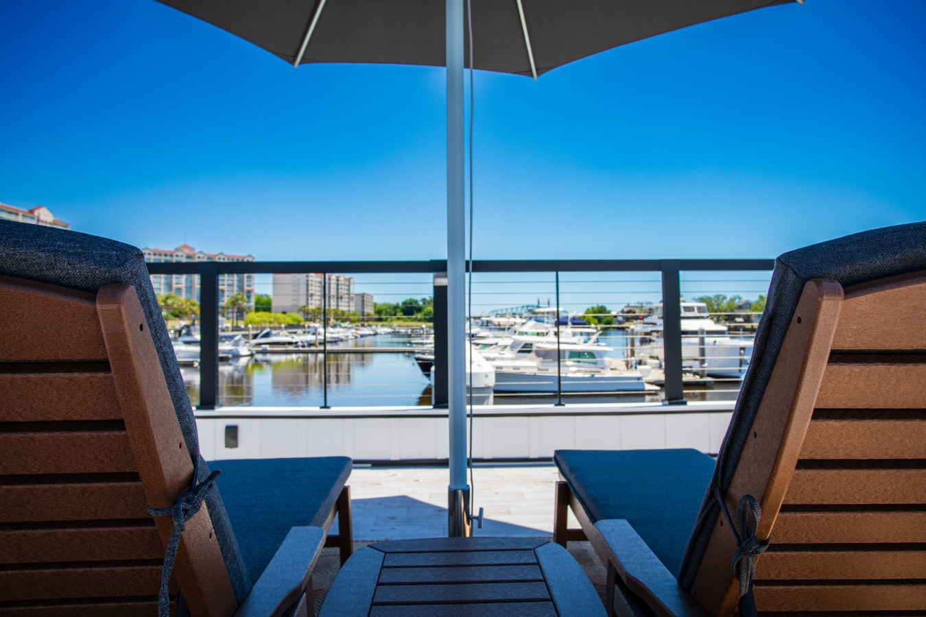 The rooftop chaise lounge view looking out over the marina, with yachts lining the docks and the Barefoot Resort towers visible across the Intracoastal.