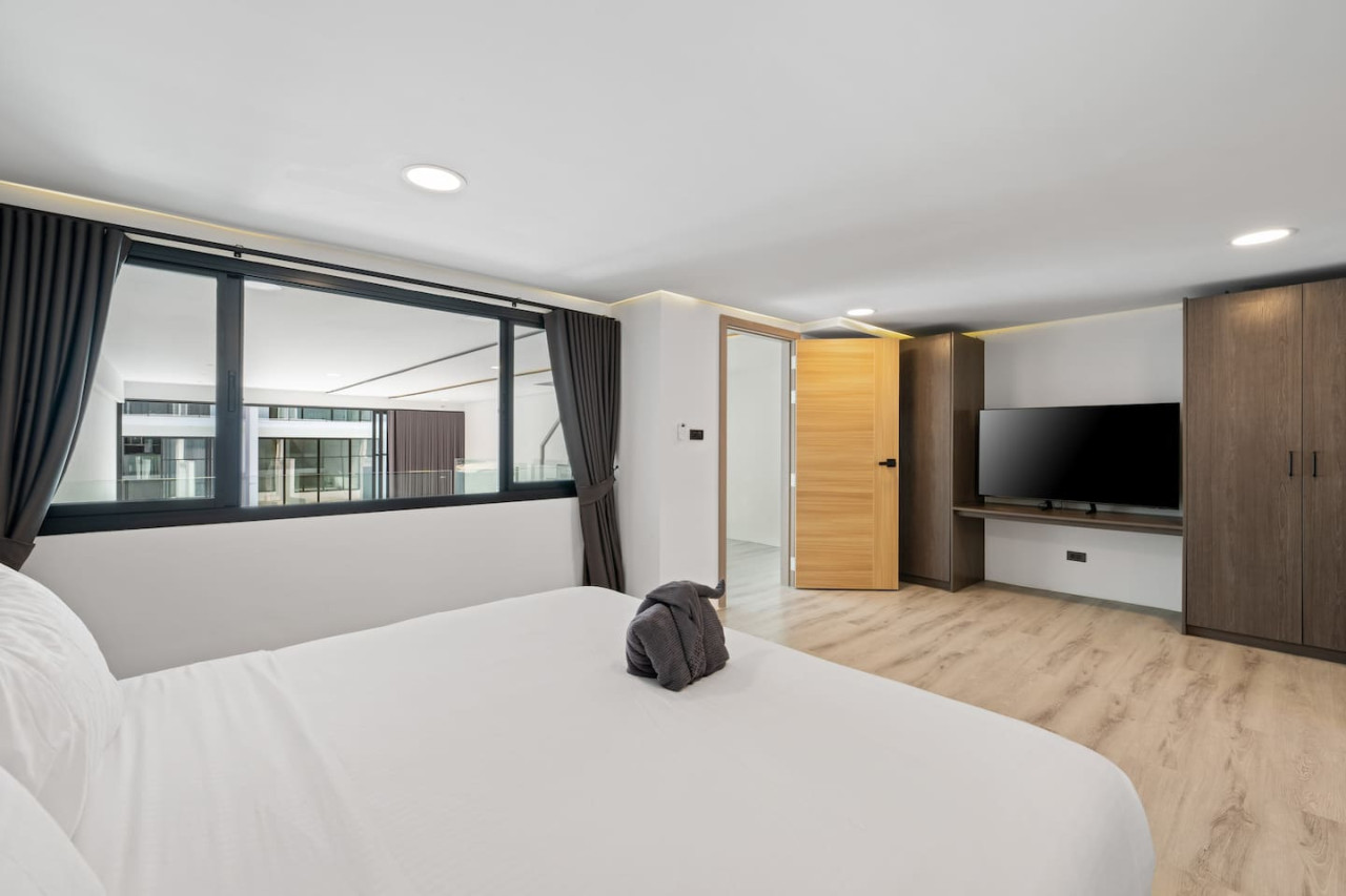 Second bedroom with warm wood flooring and garden outlook at Replay Residence Koh Samui
