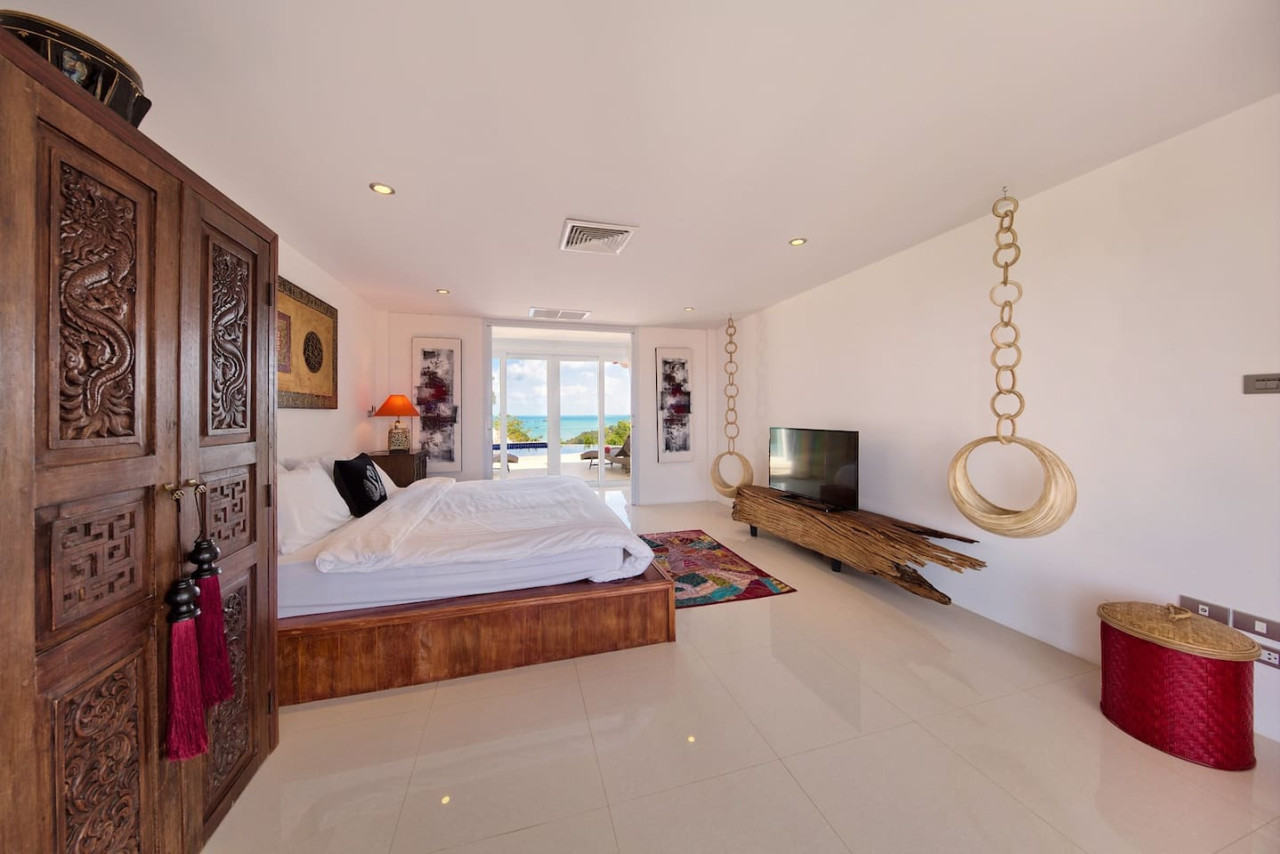 Bedroom with traditional Thai carved doors and hanging chair Koh Samui