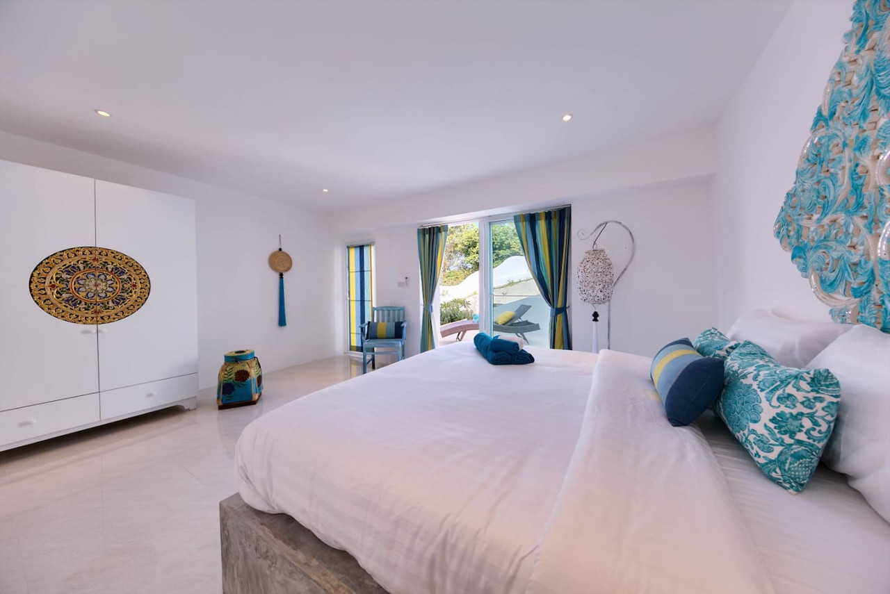 Spacious master bedroom with turquoise accents and garden views Samui