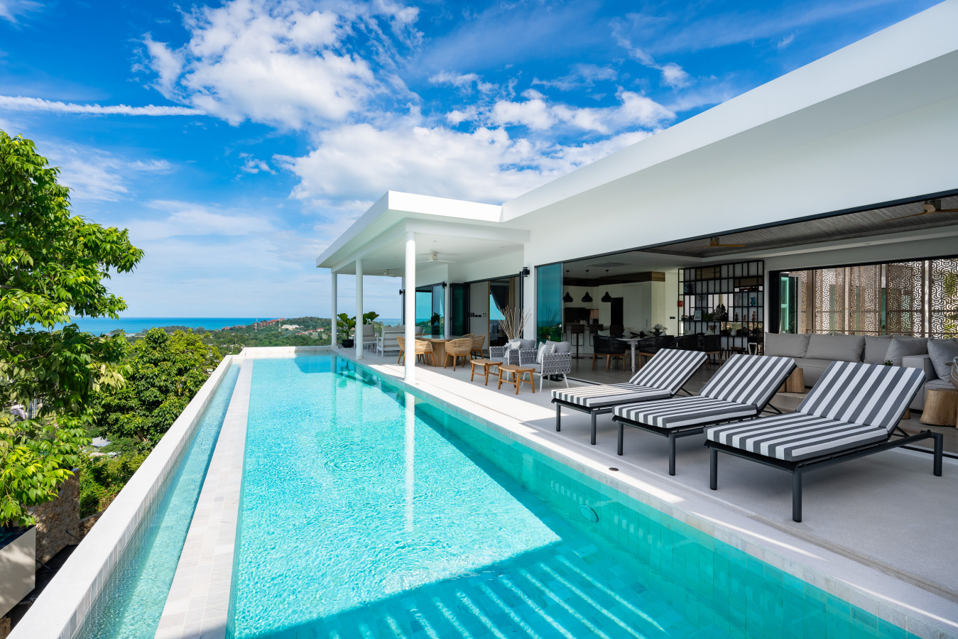 Relaxing pool deck with striped sun beds and sea backdrop