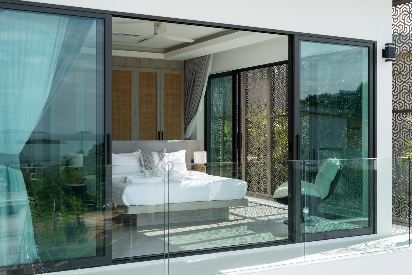 Bedroom with floor-to-ceiling glass doors opening to the pool