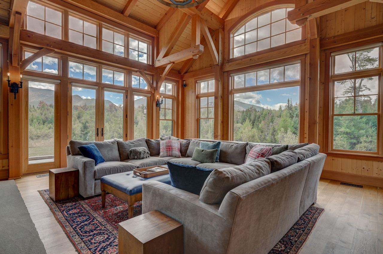 Stunning great room with a spacious sectional, large fireplace, and breathtaking panoramic views of Cannon Mountain. Perfect for relaxing with family or watching TV by the fire.