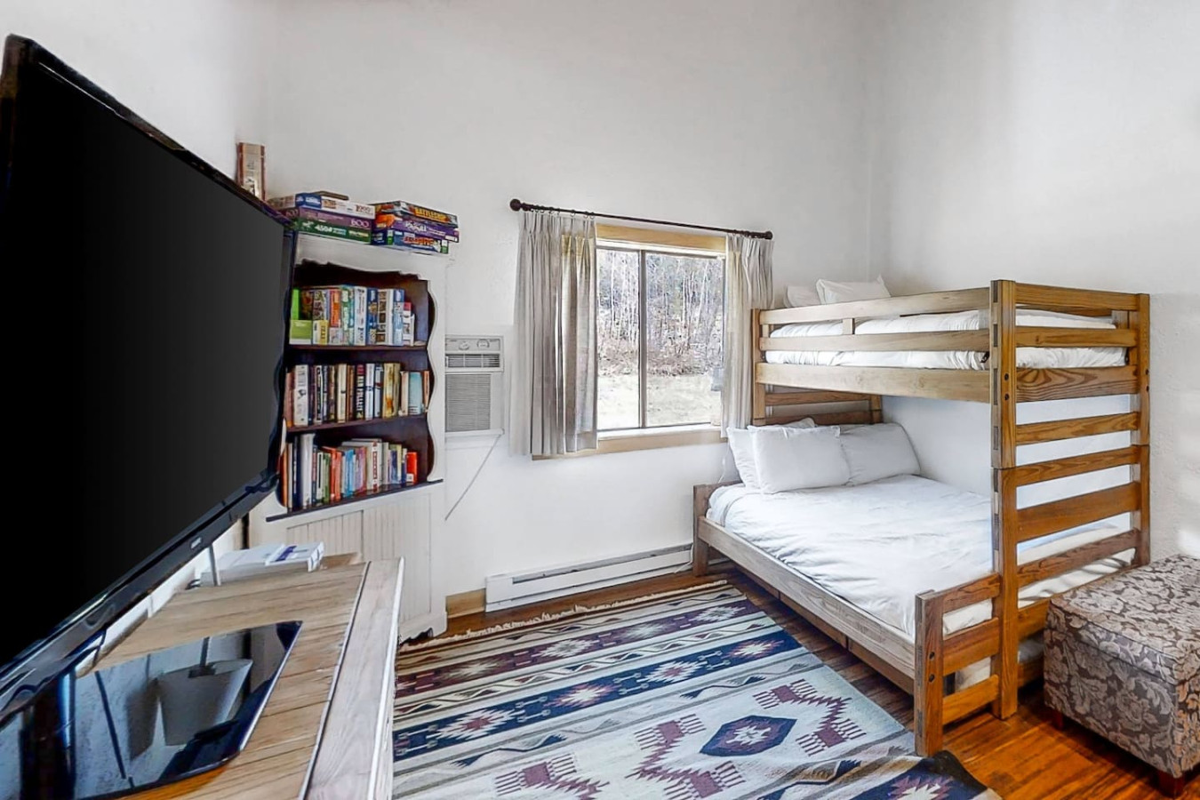 Cozy kids' room with a twin-over-full bunk bed, TV, books, and board games—perfect for fun and relaxation after a day of adventure!