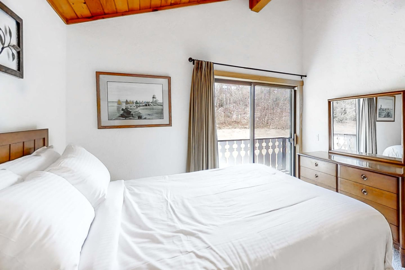 Cozy master bedroom with a queen bed, vaulted wood ceiling, and sliding door access to the back balcony—perfect for a peaceful retreat.