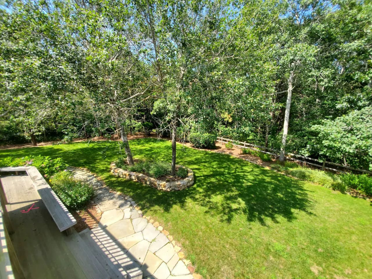 Private, beautifully landscaped backyard with stone patio, lush lawn, and mature trees. Ideal for relaxing, outdoor dining, or letting the kids play after a day at the beach. A quiet oasis surrounded by nature.