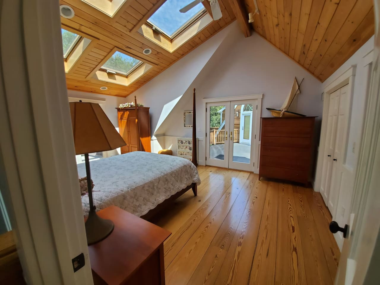 Spacious master bedroom with vaulted wood ceilings, skylights, and private deck overlooking the backyard. Features an attached full bathroom and plenty of natural light for a relaxing retreat.