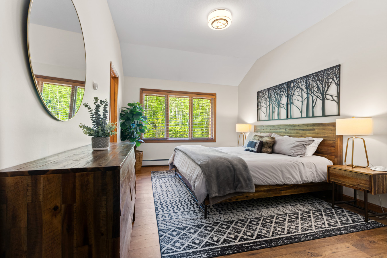Peaceful ensuite with a king bed, forest views, cozy linens, rustic decor, and private bath—perfect for rest and relaxation.