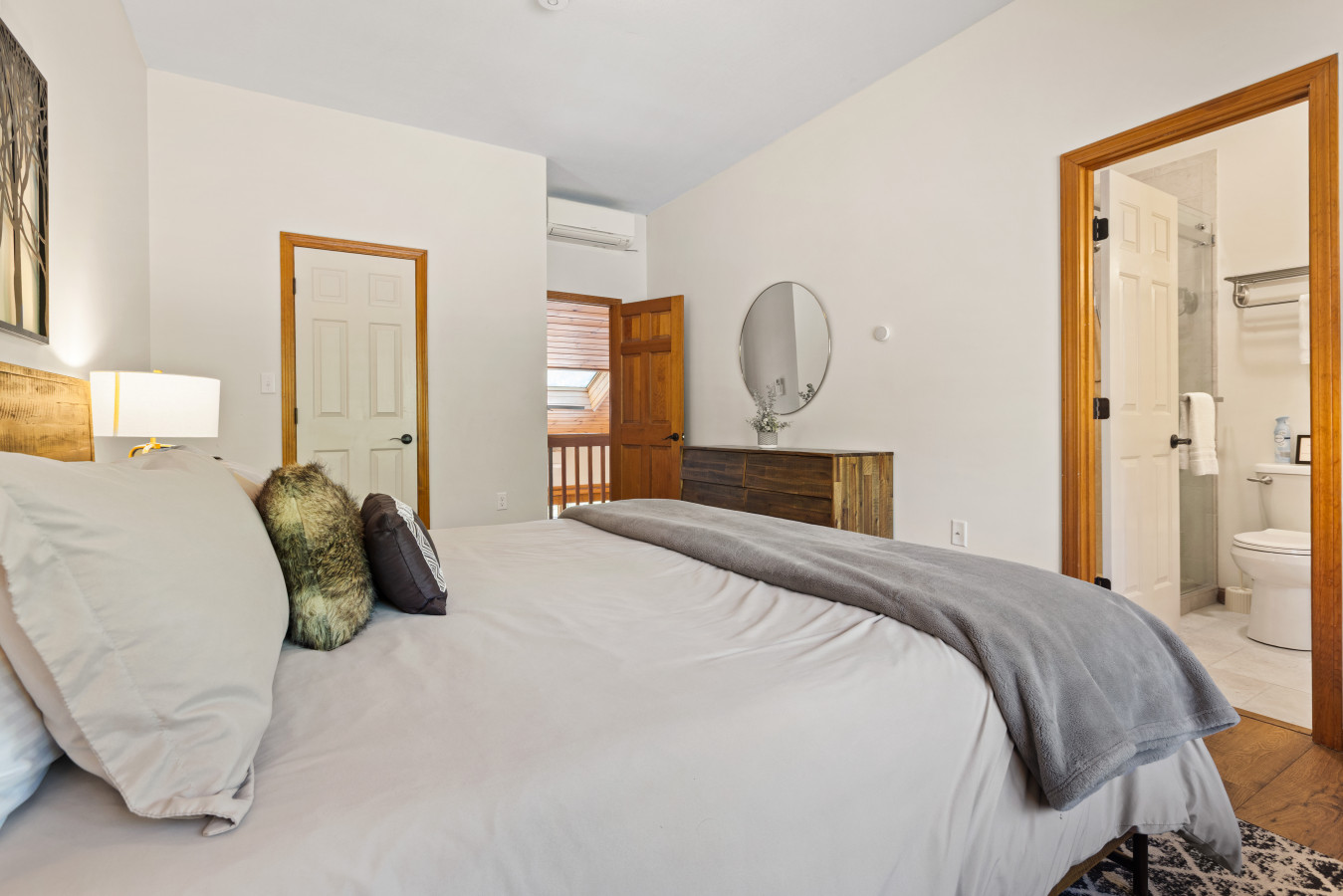 Peaceful ensuite with a king bed, forest views, cozy linens, rustic decor, and private bath—perfect for rest and relaxation.