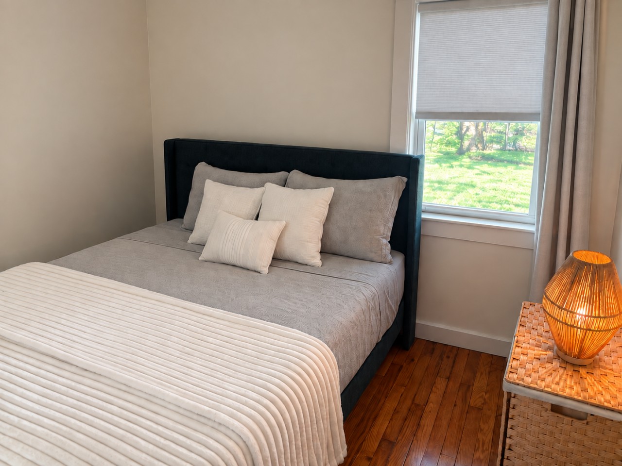 Cozy, thoughtfully styled bedroom with blackout curtains and a pull-down shade for a comfortable night’s sleep.