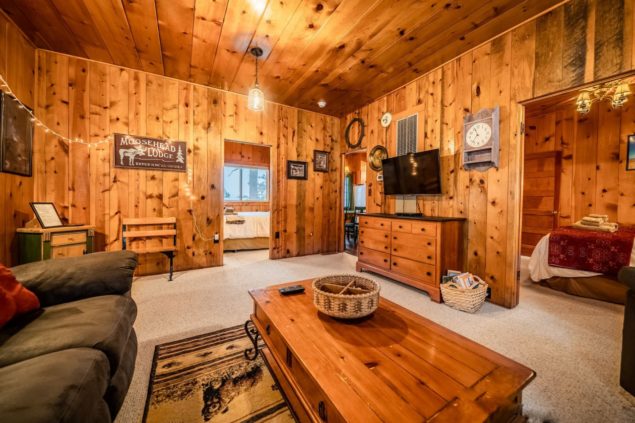 This interior cabin view is taken basically from the fireplace. The door to the right goes to one bedroom, the door to the left goes to another bedroom, and the door in the rear corner of the room leads into the kitchen.