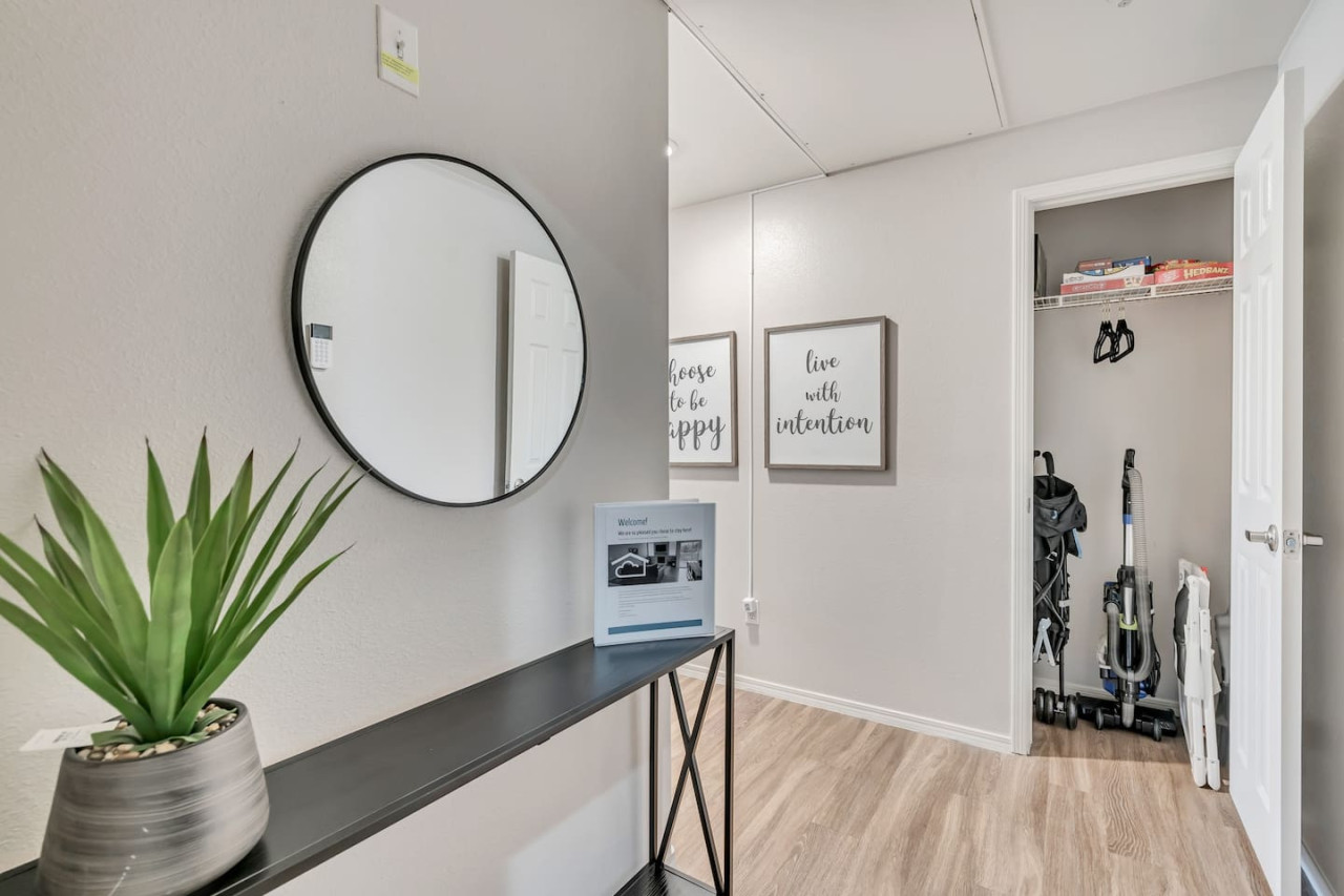 Front entry with a coat closet that includes hangers, a vacuum, mop, broom, highchair, stroller and card and board games.
